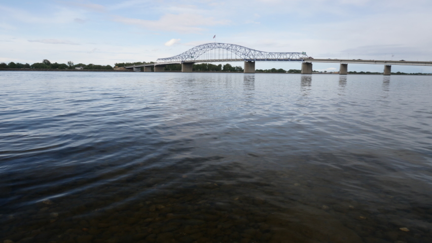 The Pioneer Memorial Bridge crosses the wide Columbia River and connects Pasco, Washington to Kennewick, Washington on a sunny day.  The bridge is a four-lane arch truss design.
