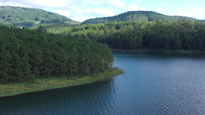 Aerial view of green forest and lakeshore. Green forest, mountain lake summer natural landscape with turquoise lake and pine tree forest. Over beautiful turquoise mountain lakes and green forest