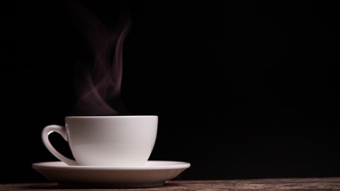 Close up coffee cup with natural steam smoke of coffee on dark background with copy space, slow motion. Hot Coffee Drink Concept.