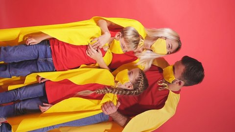 Portrait of confident super family in yellow medical masks isolated on red background, parents with kids protect themselves from covid-19