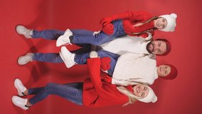 Poisitve caucasian family with children waiting for Xmas or New Year 2021, wearing warm winter clothes, shine with happiness, isolated on red background.