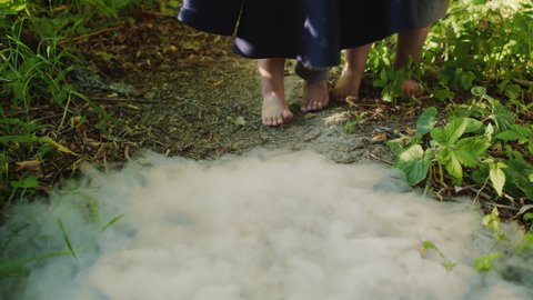 Little toddler boys barefoot legs escaping, backs away from mystic smoke on ground in forest. Hobbits, gnomes cosplay. Halloween kids concept.