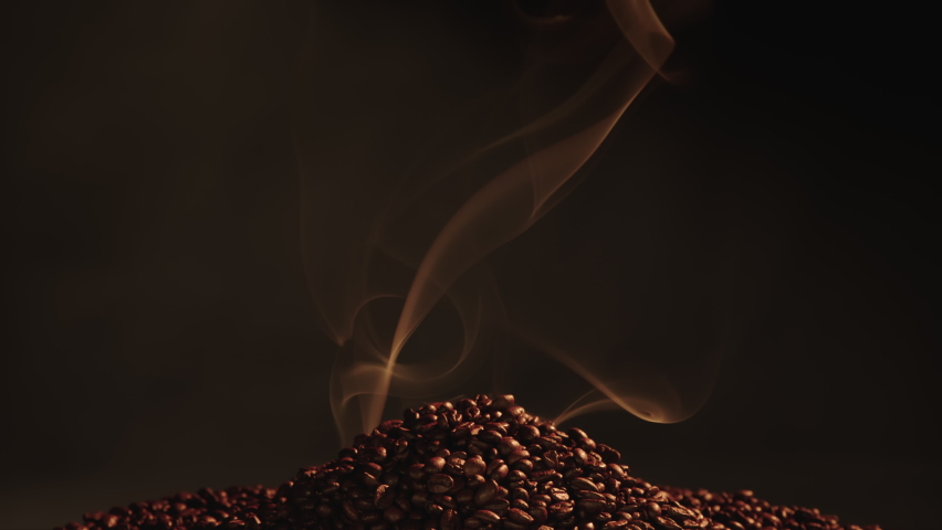 Coffee seeds smoking. Smoking coffee beans. Smoke comes from coffee beans. Pile of coffee beans smoking.