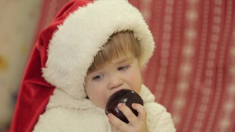 5.12.2020. Kiyv Ukraine - A 2 years old boy dressed as a polar bear wearing a santa claus hat eats an apple. Baby close up