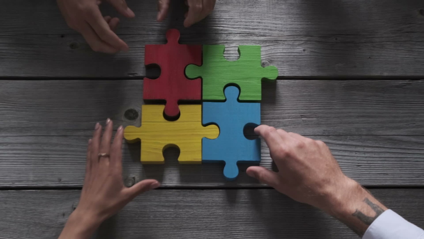 Business people team sitting around meeting table and assembling color jigsaw puzzle pieces unity cooperation ideas concept | Shutterstock HD Video #1063527445