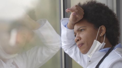 Black female doctor standing by the medical office window with negative expression