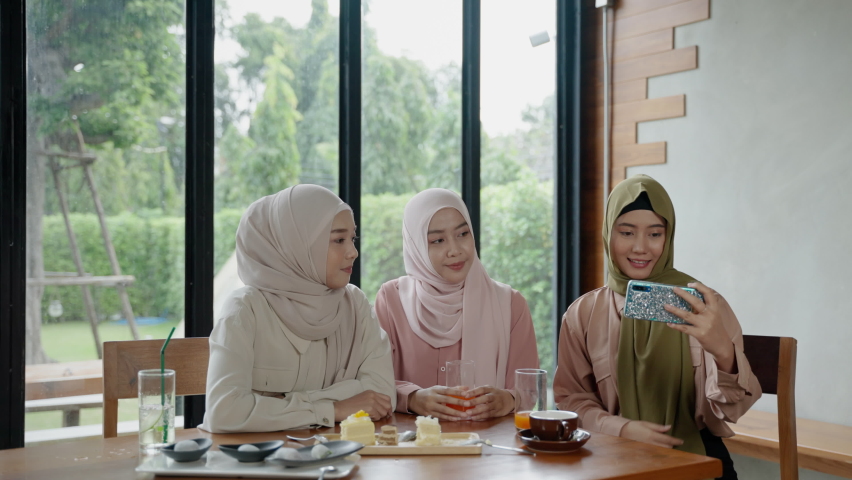 group of Muslim girls dining in a restaurant is using their mobile phones to selfies to show in social media.
 Royalty-Free Stock Footage #1063527586