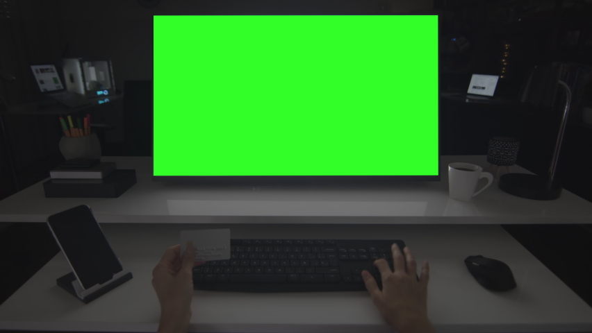 Online shopping.  Locked shot of female caucasian hands holding a credit card and typing information on a keyboard. Desktop computer with chroma key.  Track corners with perspective corner pin.  Royalty-Free Stock Footage #1063529155