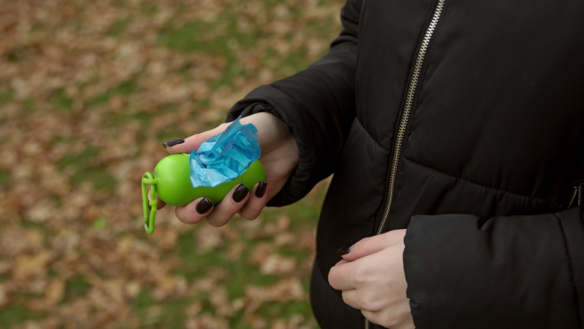Girl tears off a plastic bag for dog poop. 4K, Slow motion, close-up