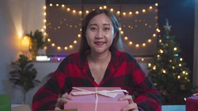 Young Asian woman using laptop for video call while happy with Christmas gift box