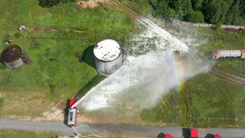 Firefighter or fireman on fire truck practicing at the training ground or range with fire extinguishing foam. Fire engine pours foam or shoots water