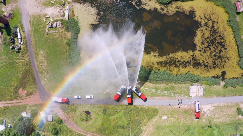 Firefighter or fireman on fire truck practicing at the training ground or range with fire extinguishing foam. Fire engine pours foam or shoots water