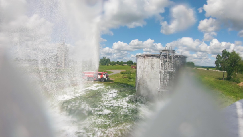 Firefighter or fireman on fire truck practicing at the training ground or range with fire extinguishing foam. Fire engine pours foam or shoots water