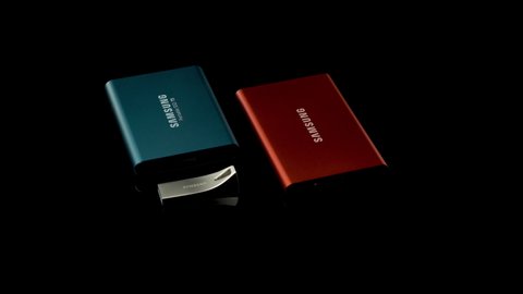 Seoul, South Korea - December 03, 2020: Samsung portable data storage systems rotating on a reflective black surface. Portable Solid State Drives and USB pen drive.