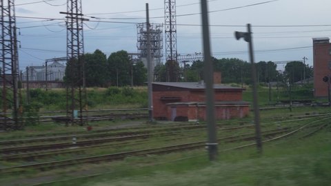 Transport, travel, road, landscape, comnication concept - view from window of speed train on landscape of nature field railway and old rusty freight wagon train in dull cloudy weather summer evening