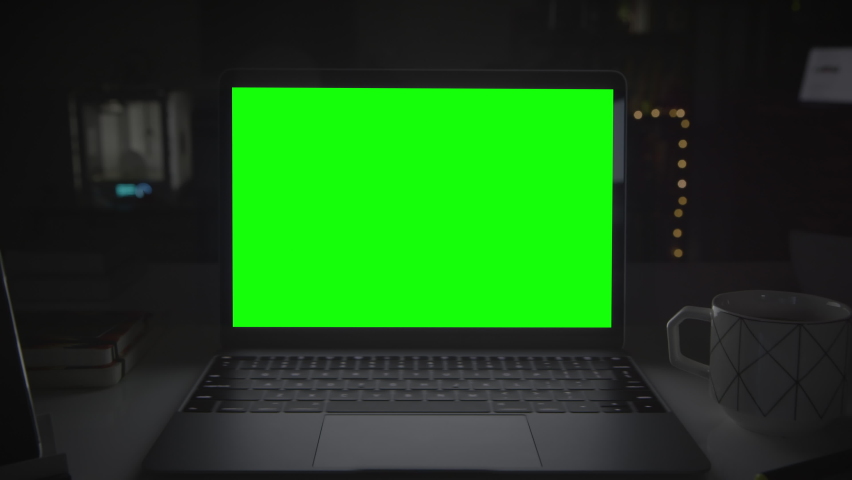 
Dolly in of laptop computer with green screen. Dark office in the background with several electronic devices. Perfect to put your own image or video. Track with perspective corner pin.   Royalty-Free Stock Footage #1063540756
