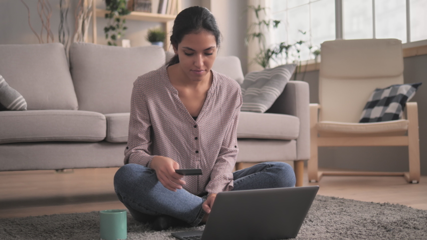 young smiling middle eastern woman sitting on the floor at home shopping on internet store using laptop,attractive adult mixed race female paying with credit card online banking e-commerce concept Royalty-Free Stock Footage #1063541983