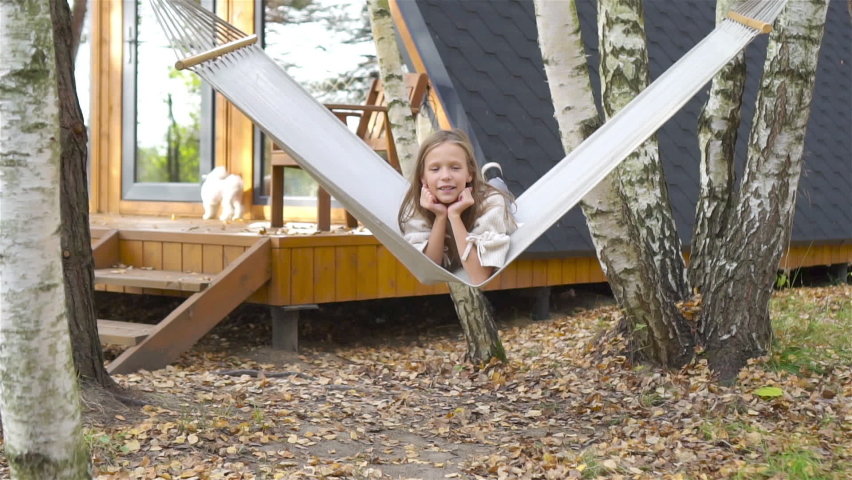 Beautiful girl enjoying autumn day outdoors having fun in hammock