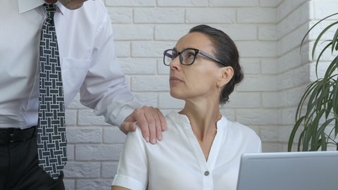 Businessman harass the woman. A man puts his hand on her shoulder in the office. A concept of harassment on the workplace.