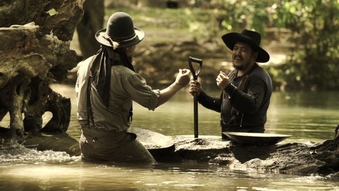 Cowboys, two men panning for gold by the river.