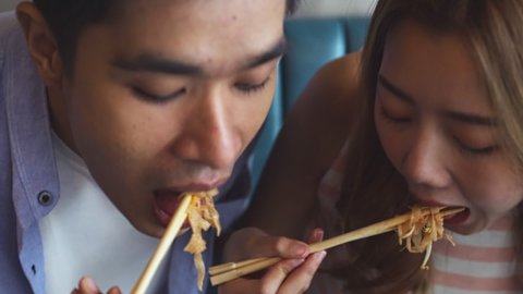 Young asian  man and woman  eating at restaurant . Couple travel and taste noodles and street food .