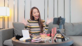 Young female influencer or youtuber recording online presentation video of beauty products and recommending them. Using a mobile on a steady tripod.