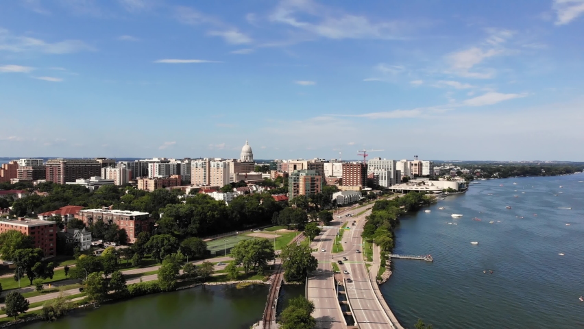 Aerial View of Madison City, Wisconsin USA. Traffic by Monona Lake and Downtown Cityscape Under Summer Sky, Dolly Drone Shot