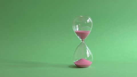 Hourglass sand timer on green background.