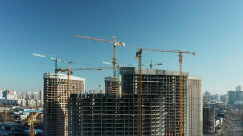 Fly over the construction site, work as construction personnel, builders work, construction houses. Aerial Flight Over a New Constructions Development Site with High Tower Cranes Building Real Estate.