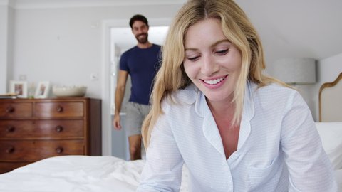 Happy couple wearing pyjamas in bedroom celebrating positive pregnancy test - shot in slow motion