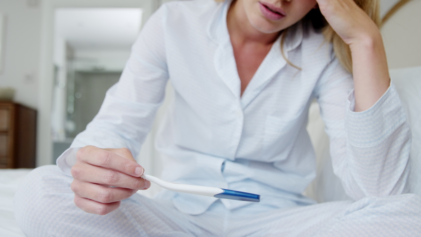 Close up of unhappy woman wearing pyjamas in bedroom holding pregnancy test - shot in slow motion | Shutterstock HD Video #1063561219