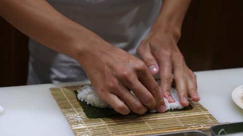 4K Professional male chef hand preparing delicious healthy japanese food menu shrimp sushi roll by rolling seaweed with rice and fried shrimp tempura together on kitchen counter in japanese restaurant
