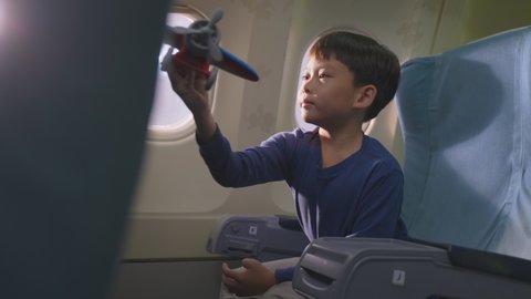 Asian young little boy playing aircraft model toy, sitting on airplane. The kid is feeling happy and excited and wants to be a pilot as his dream job to fly the plane in the future when he grow up.