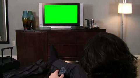 Rear view of man watching green screened television flipping channels - HD