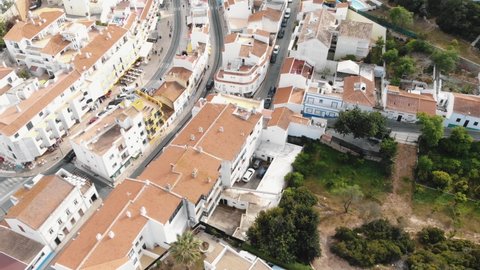 Reveal of Atlantic coast and seascape in Carvoeiro Town in Algarve, Portugal - Fly over tilt up aerial shot
