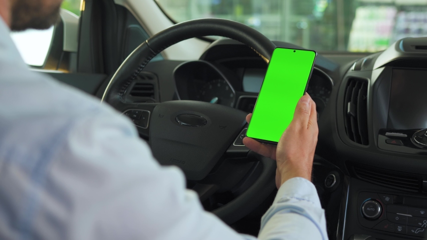 Driver using a smartphone inside the car. Chromakey smartphone with green screen. Auto navigation. Internet addiction Royalty-Free Stock Footage #1063569541