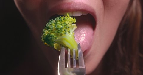Young woman mouth eating broccoli