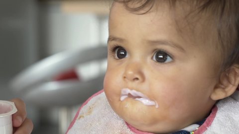 Portrait of 8-month-baby girl eating yoghurt