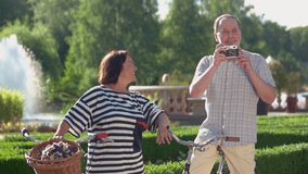 Senior couple enjoying time together at park. Cheerful mature man takes picture using film camera outdoor. People, retirement and vacation concept. - Powered by Shutterstock - Get 15% off with code: PIKWIZARD15