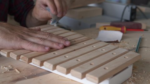 Eco toys and musical instruments made of wood. A master carpenter makes a handmade xylophone for children.