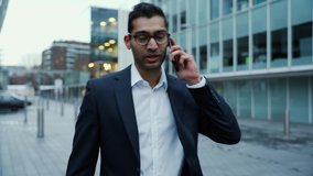 energised mixed race businessman walking home from work chatting on cellular device after long day at work