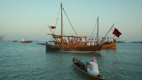 Doha, Qatar - December 5 2020: Katara tenth traditional dhow festival in Doha Qatar afternoon shot showing Traditional Oman folklore dance group performing on a dhow with Qatar Flag in Arabic gulf