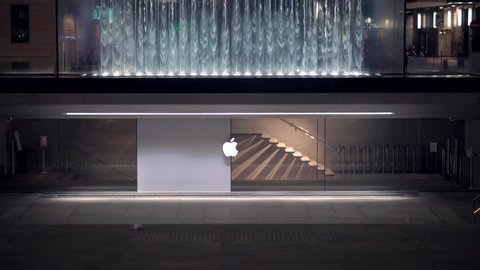 Deserted city streets during a pandemic in Milan. Coronavirus (COVID-19. Stores closed sails. Pandemic. Liberty Square Apple store in the evening. Logo. Artificial noise. Milan, Italy - December 2020:
