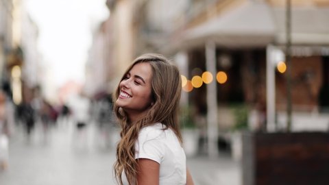 Young beautiful blonde woman spinning in the center of a city. Attractive fashion model with flying hair. Beautiful girl woman shakes hair. Slow motion