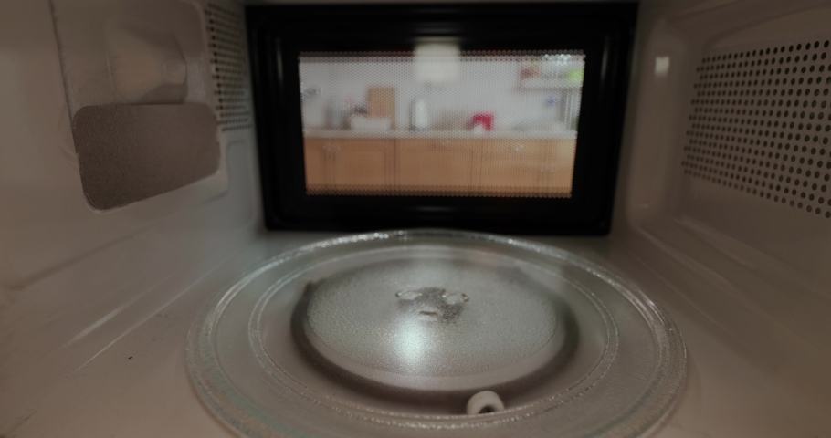 Heating food in a microwave viewed from inside the back, plate of pasta with salmon, turning on Royalty-Free Stock Footage #1063604062