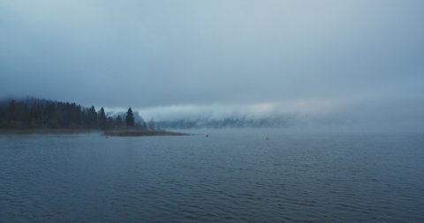 Mist is rising during a foggy break of dawn, while winter is coming over the countryside of lake Mondsee, Austria