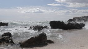 Time lapse video of sea with waves breaking against rocks on a windy day on Molho beach, Spain