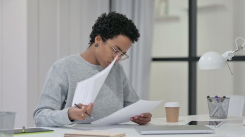 Young African Woman Reading Papers at Work 