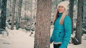 Young woman in forest on winter day. Hiker hugging tree trunk. Save of nature and the planet. 4K video