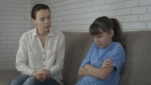 Displeased teen. Mother try to speak with depressed teen in the room.